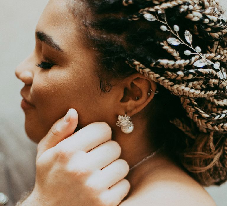 Bride with soft smoky eye with her braids in an updo and a pearl and silver earring and hair accessory 