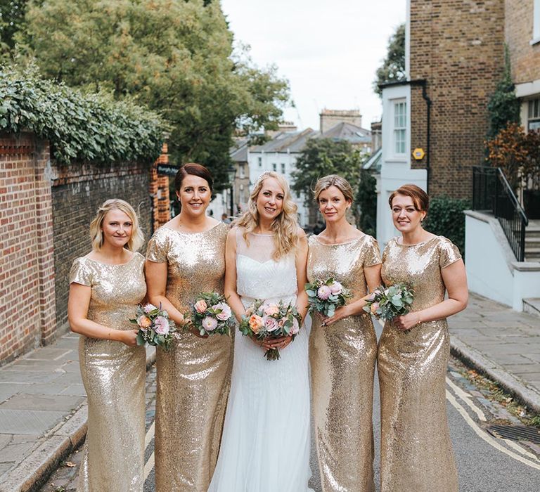 Bridesmaids in full gold sequin dresses with the bride in white beaded wedding dress