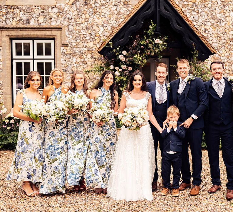 Groom, groomsmen and page boys in blue suits, bridesmaids in blue floral dresses and the bride in a bespoke Phillipa Lepley wedding dress