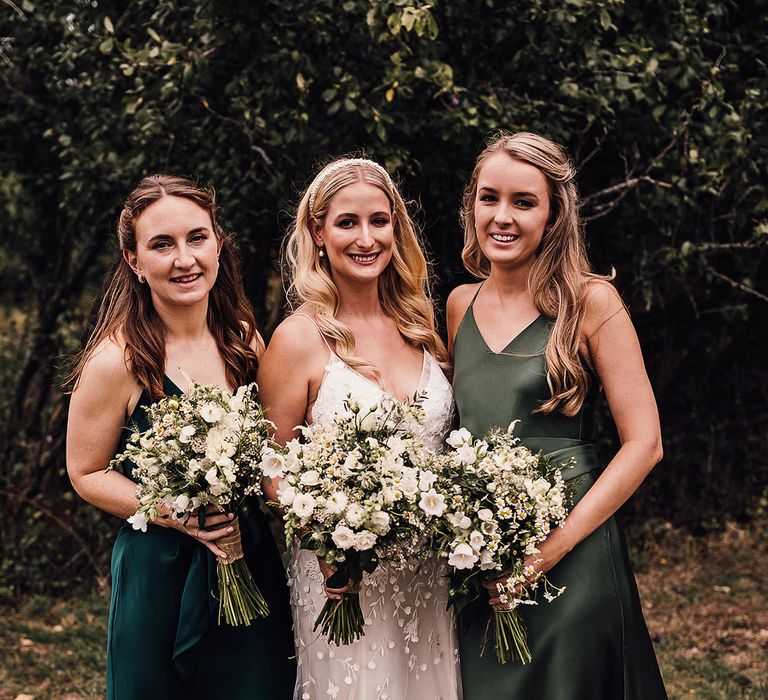 Bride in an applique Alexandra Grecco Lana wedding dress with her bridesmaids in different shades of green satin dresses 