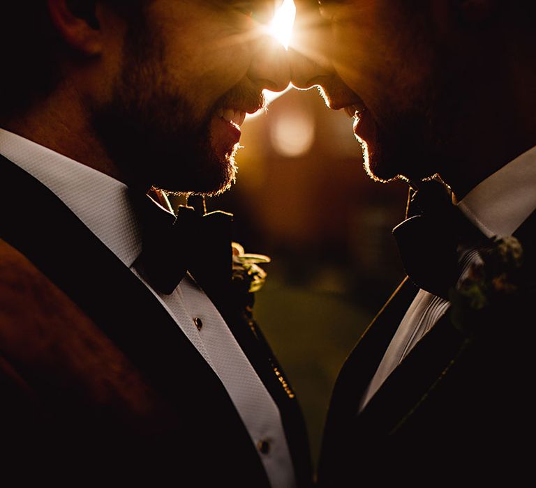 Grooms embrace outdoors during golden hour portraits