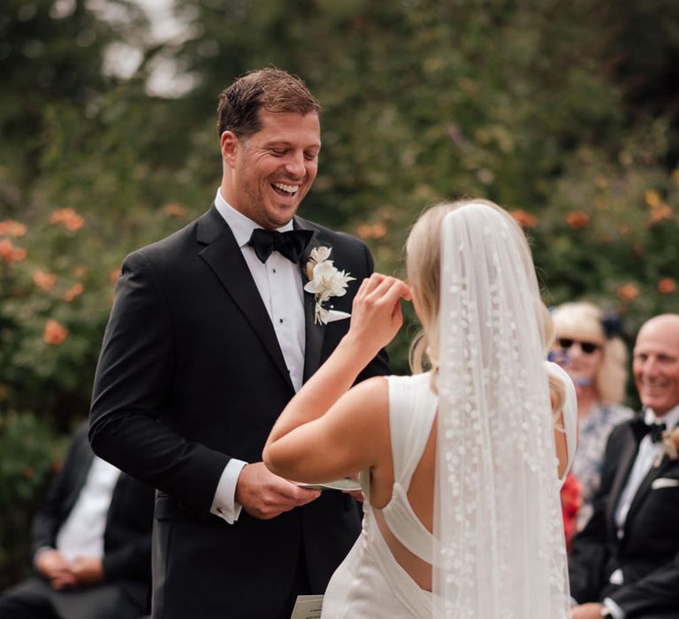  The groom in a black tuxedo reads out his wedding vows for the humanist wedding ceremony 