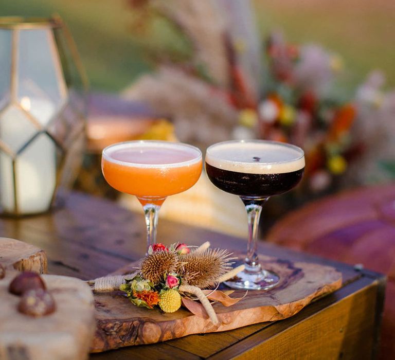 Espresso martini and orange drink in cocktail glasses with dried flower, rose and pampas grass boutonniere on a wooden slate