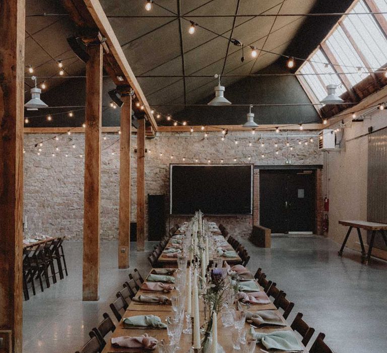 Industrial styled wedding venue with wooden banquet tables and DIY decor 