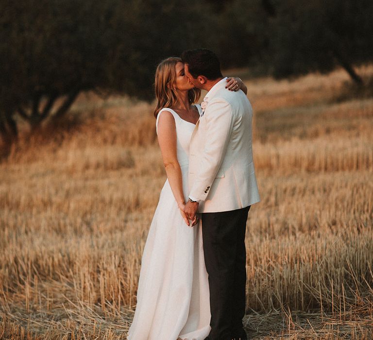 Bride & groom stand outdoors for couples portraits during golden hour