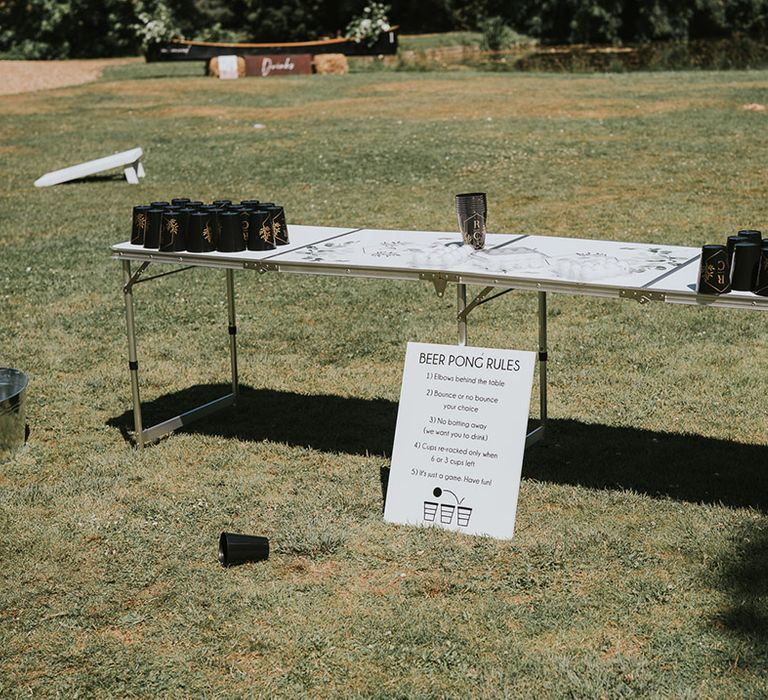 Outdoor table set up with personalised black cups ready for games of beer pong 