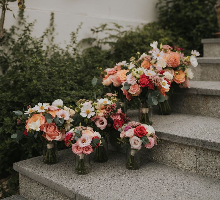 The bride's, bridesmaid's. and flower girl's bouquets with red and pink roses, pink dahlias, white cosmos and more 