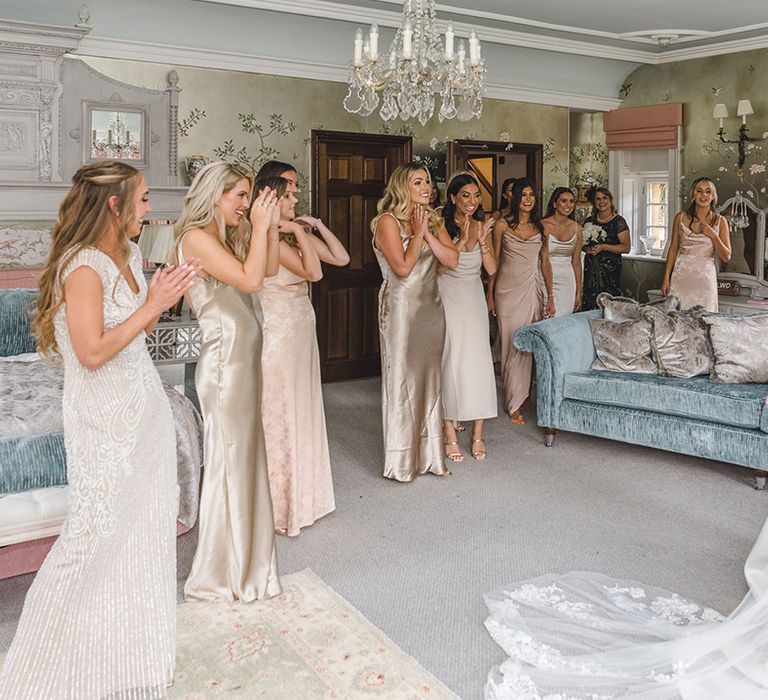 Bridesmaids in mismatched gold bridesmaid dresses for the wedding all looking at the bride for the first time 