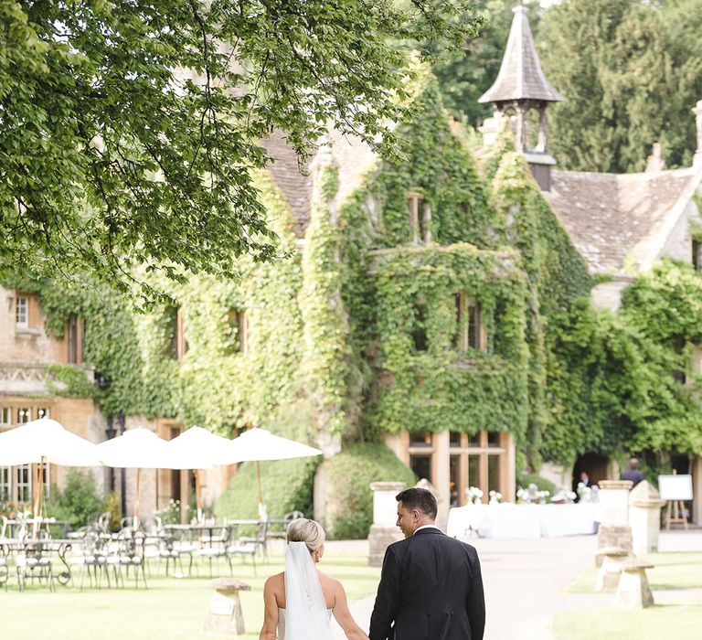 The Manor House, Castle Combe wedding venue with the bride in a fitted mermaid wedding dress and groom in morning suit 