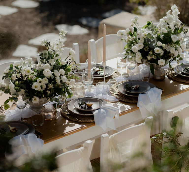 Wedding tablescape with white roses, white berries, italian ranunculous and eucalyptus, figs, ribbed jars and blush tapered candles