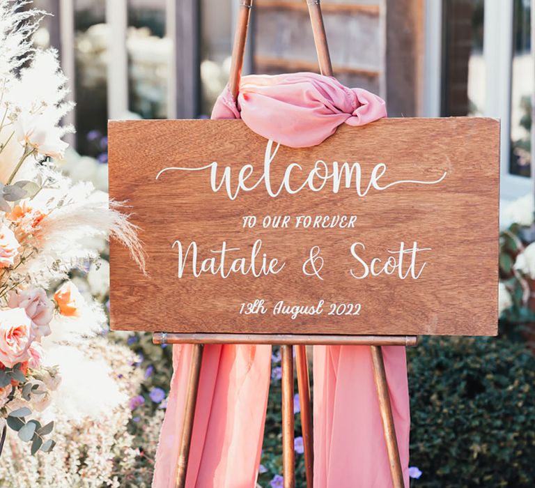 Wooden rustic wedding welcome sign with pink drapery with pampas grass decor 