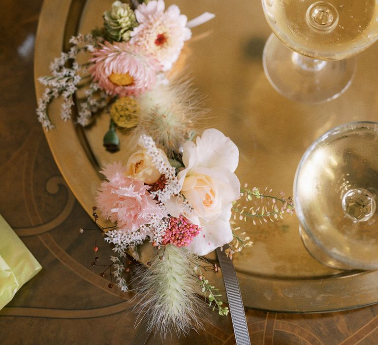 The groom's and best man's pink buttonholes on gold tray with glasses of champagne 