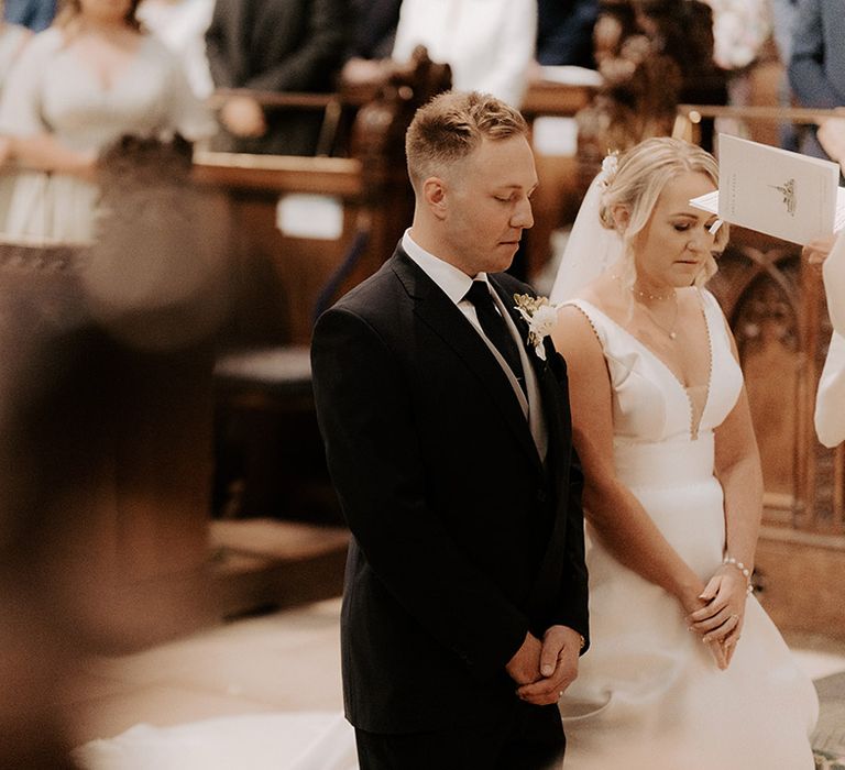 The bride and groom kneel at the wedding altar for their church prayers 