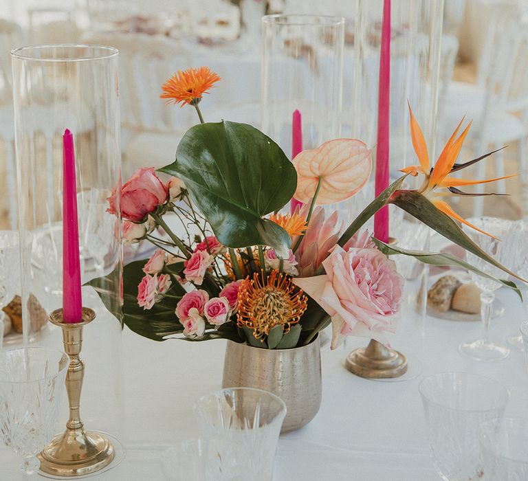 wedding table centrepiece with tropical flower arrangement and pink taper candles