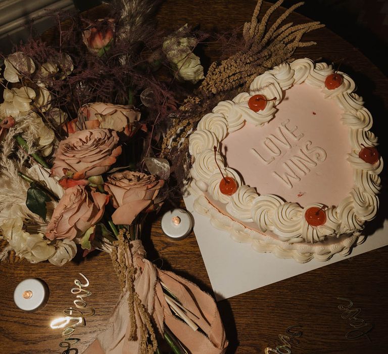 Single tier heart shaped pale pink wedding cake with white piping and cherries 