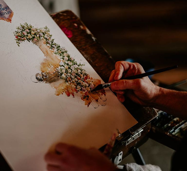 A live illustration artist attending a farm wedding venue painting the wedding ceremony 