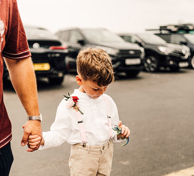 Page boy in white shirt, beige short and braces for beach wedding 