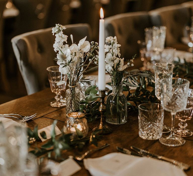 White classic flower arrangements with white candles decorating the tables 