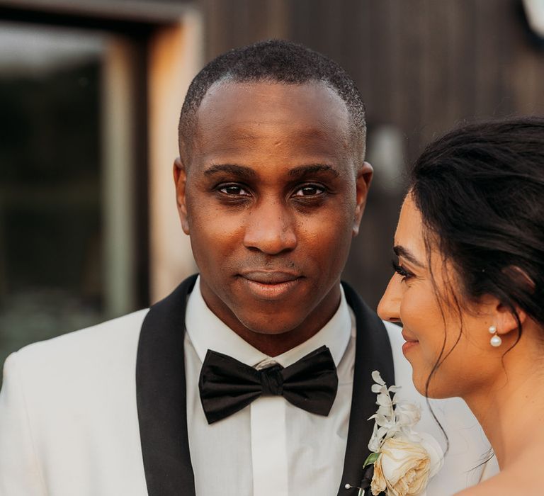 Black groom in white tuxedo jacket and black bow-tie at Crumplebury wedding