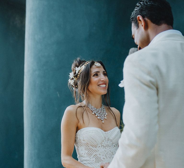 Groom in white suit takes first look at bride in lace wedding dress and flower hair accessories