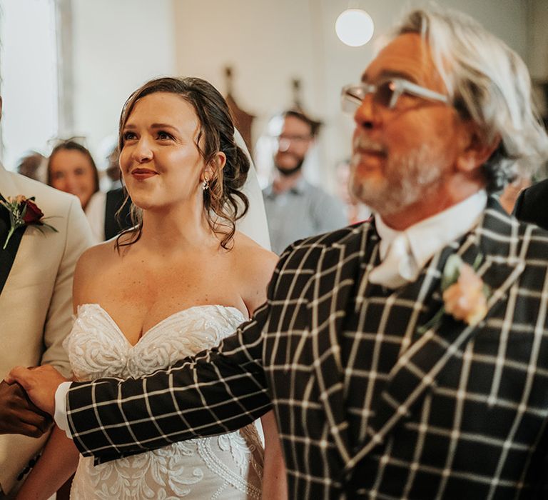 Father of the bride in checkered black and white suit standing with he bride at the altar for church ceremony 