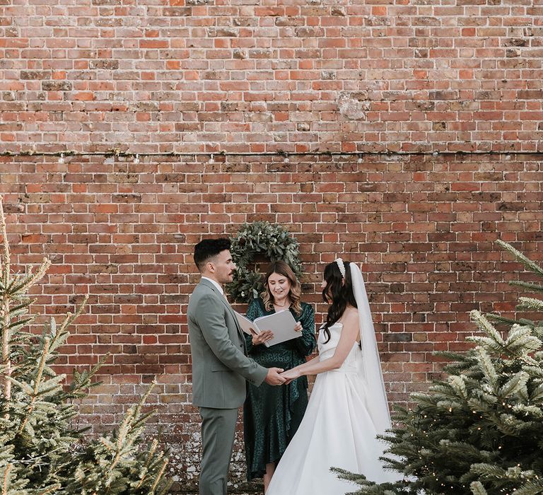 Ripple Court Estate at an outdoor wedding ceremony with the bride wearing a princess gown and groom in a green suit 