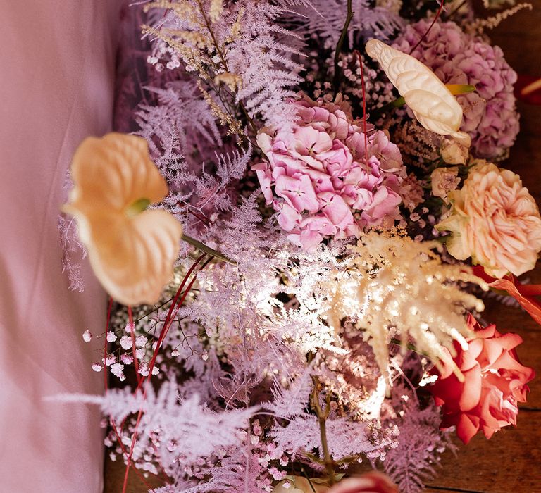 Purple, pink and orange pastel wedding flower decorations with anthuriums and gypsophila 