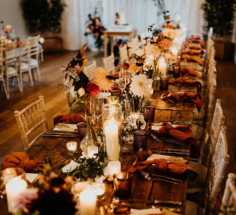 Candlelit orange autumnal wedding table decorations with dahlias in bud vases 