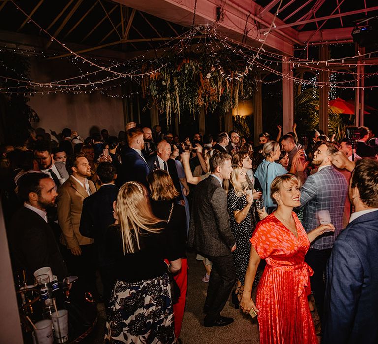 Wedding reception with wedding guests dancing around with fairy lights and live wedding band performing 