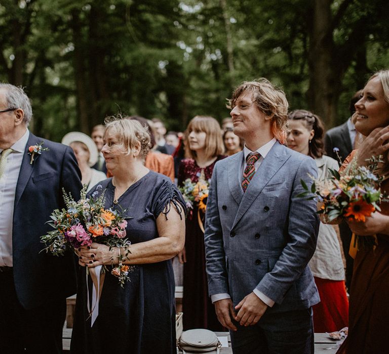 The wedding party at the wedding ceremony watches the couple exchange their vows 