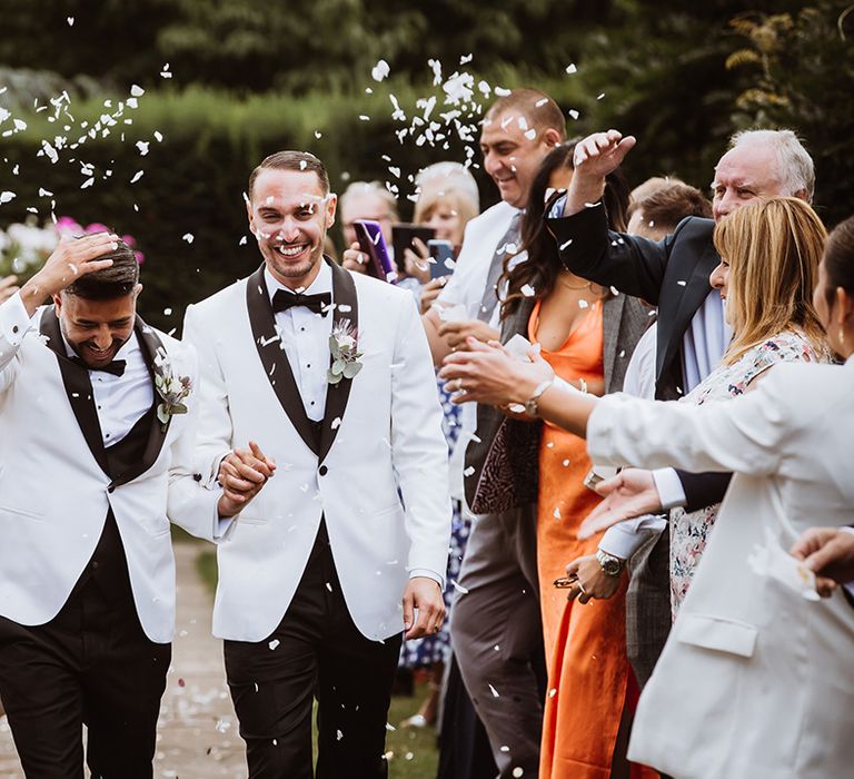 Classic confetti exit for two grooms as they walk out of their wedding ceremony as a married couple 