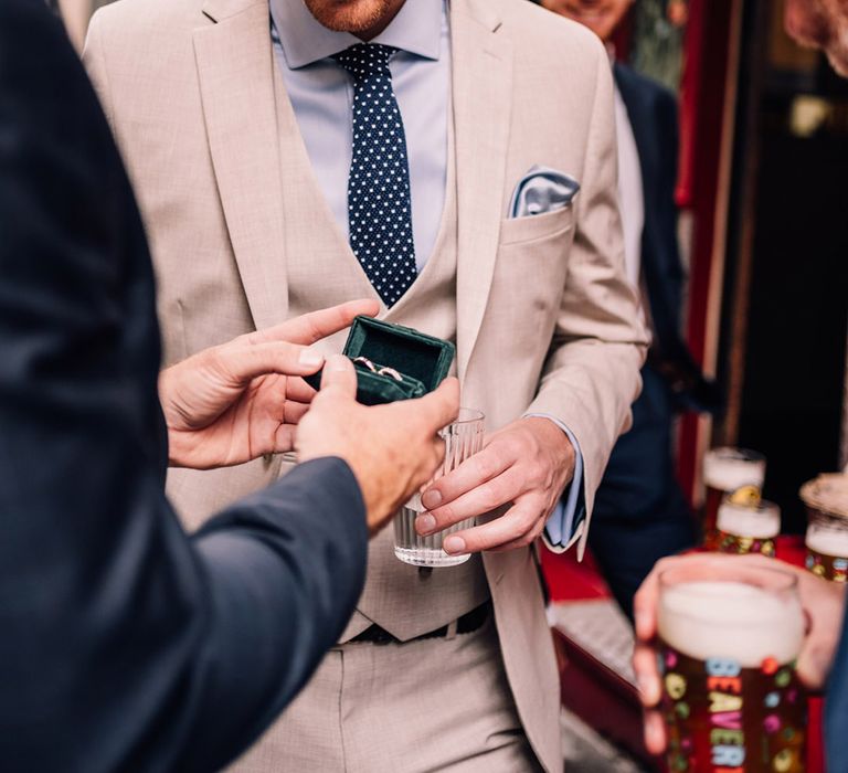 Groom shows the groomsmen the wedding bands in a green ring box