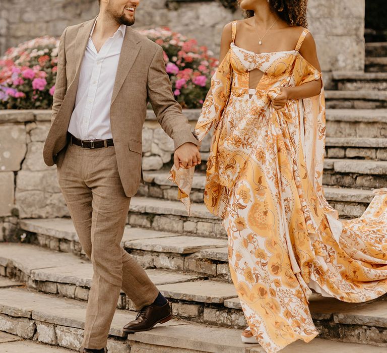 Bride in yellow and white colourful wedding dress walking hand in hand with the groom 