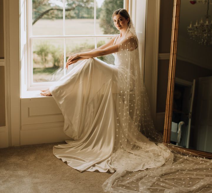 Bride sits beneath Georgian window at Reymerston Hall