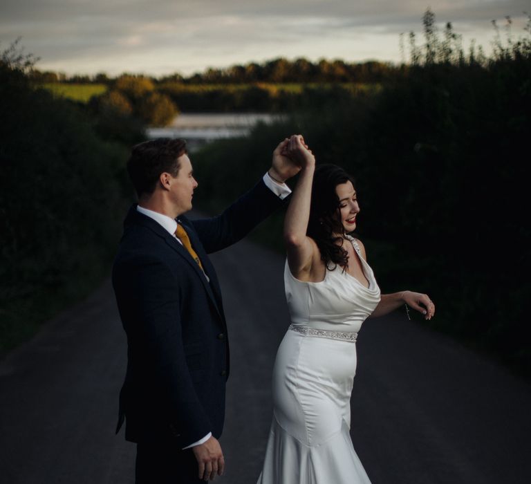 Groom twirls bride outside 