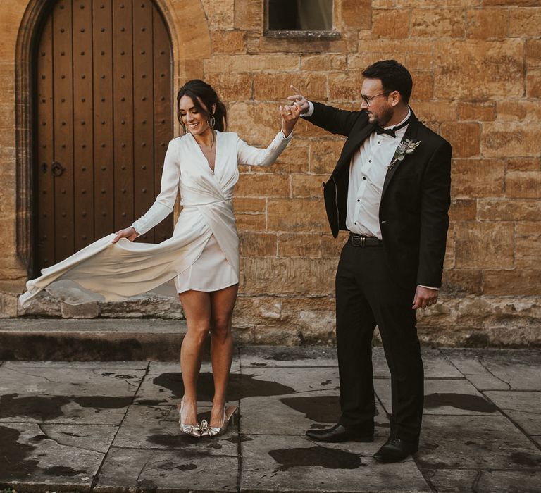 Bride & groom dance together with brides dress blowing in the wind