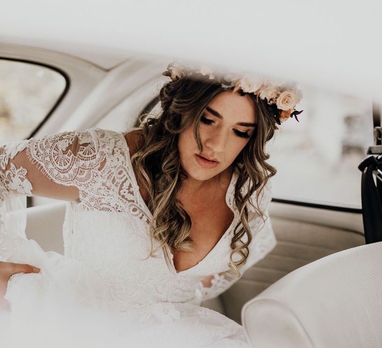 Boho bride with rose flower crown and curled wedding hair in the back of vintage wedding car