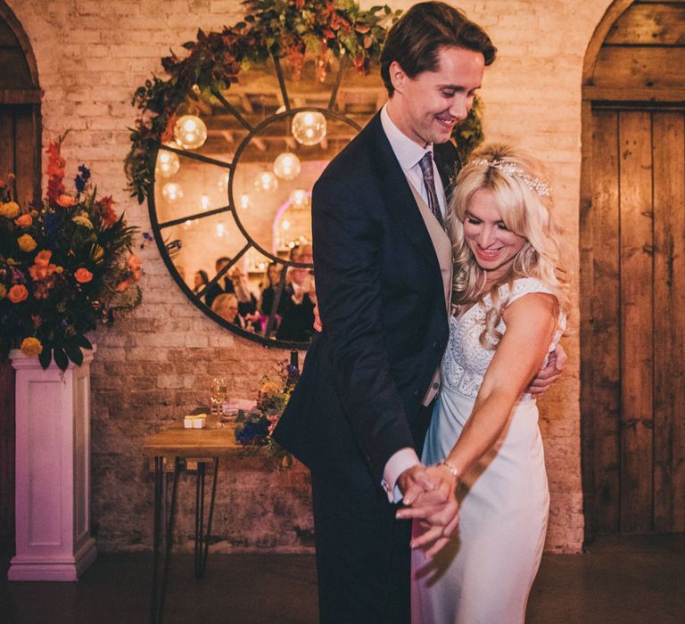 Bride in Justin Alexander wedding dress and pearl headband dances with groom in navy suit and beige waistcoat at Iscoyd Park wedding reception