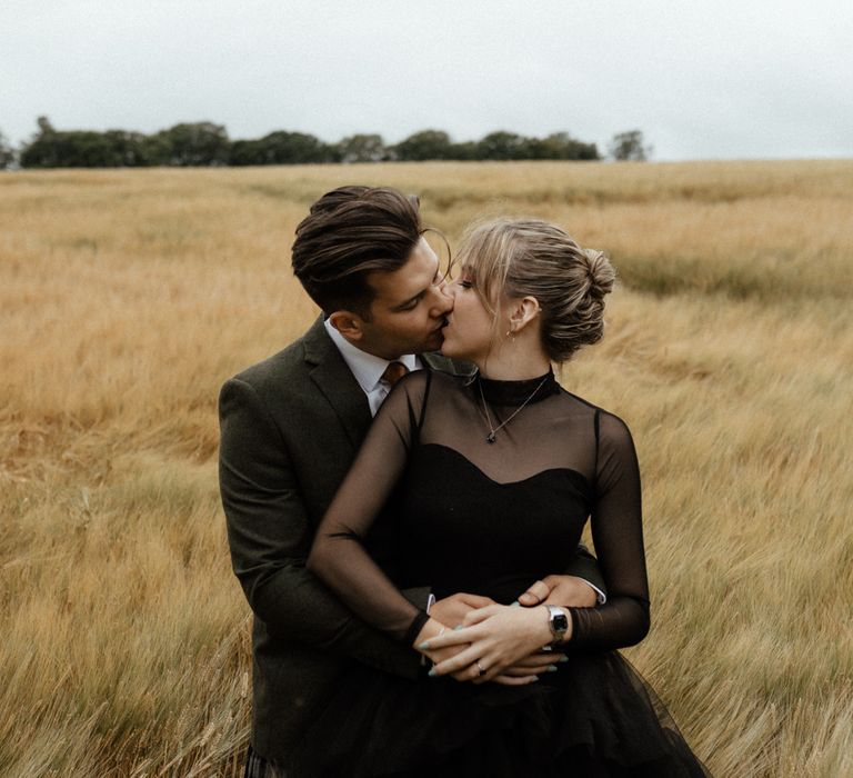 Bride looks back at groom in golden fields on wedding day