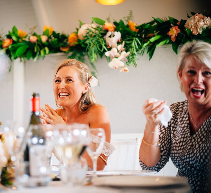 Bride laughing at wedding breakfast with peach wedding flowers in the background