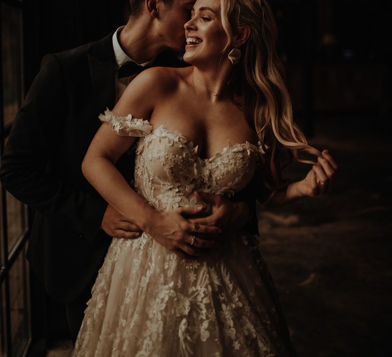 Bride with long wavy hair in a lace wedding dress with fitted bodice and off the shoulder detail 