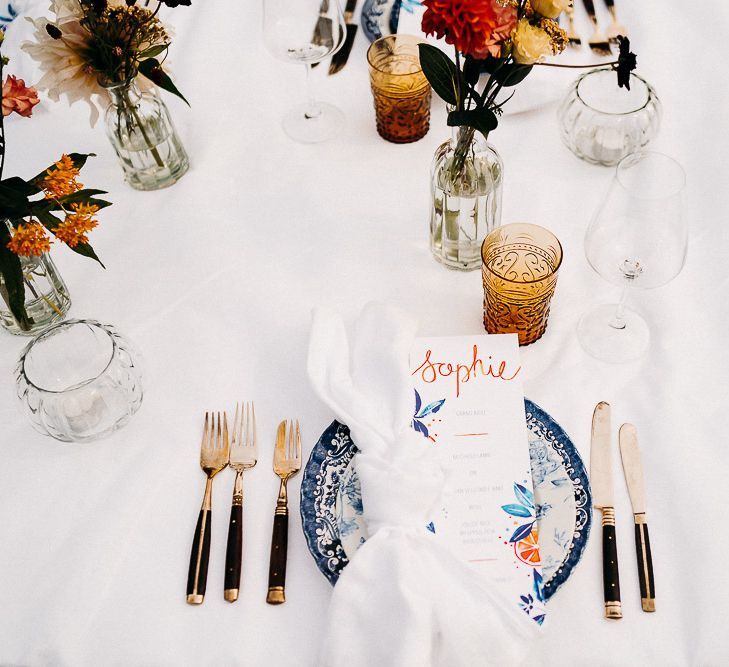 Place setting with blue and white china, yellow glassware and black cutlery 