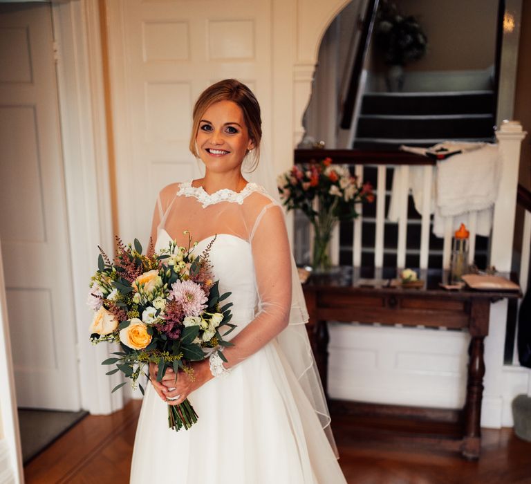 Bride wears long sleeved wedding dress with blonde hair in low updo