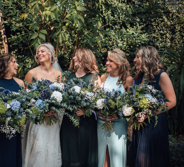 Bride laughs with her bridesmaids holding homemade bouquets before wedding ceremony