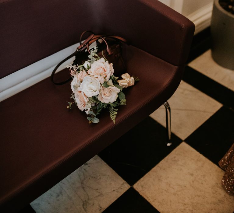 Pink and white rose wedding bouquet resting on a chair 