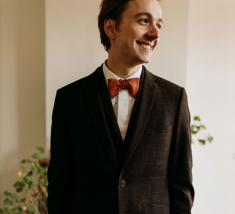 Groom in a three-piece check suit and orange bow tie 