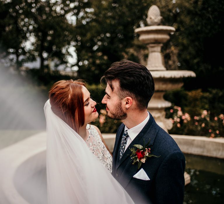 Bride & groom kiss as her veil blows in the wind outdoors