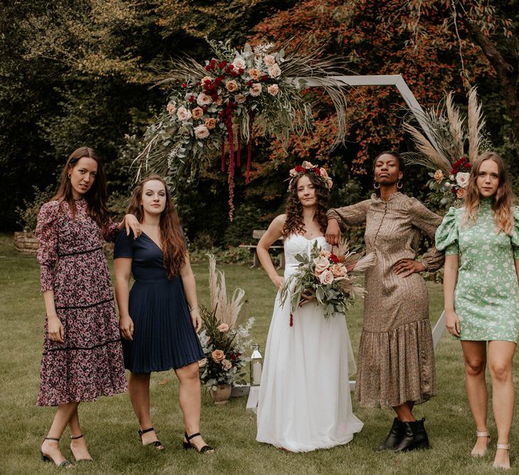 Boho bride in ASOS wedding dress and flower crown standing with her girls friends in front of a wooden altar 