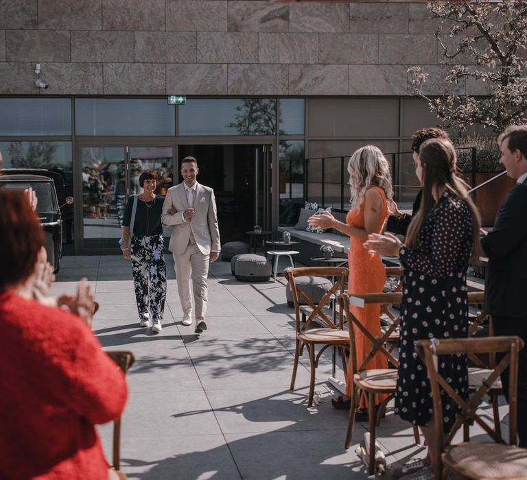 Groom walking down the aisle with his mother at gay wedding