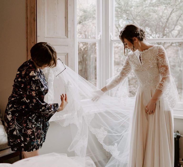 Bride getting ready on the morning of her wedding wearing lace bodice wedding gown